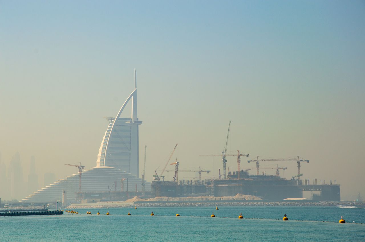 Home View of the Burj Al Arab and construction cranes in Dubai, showcasing urban development.